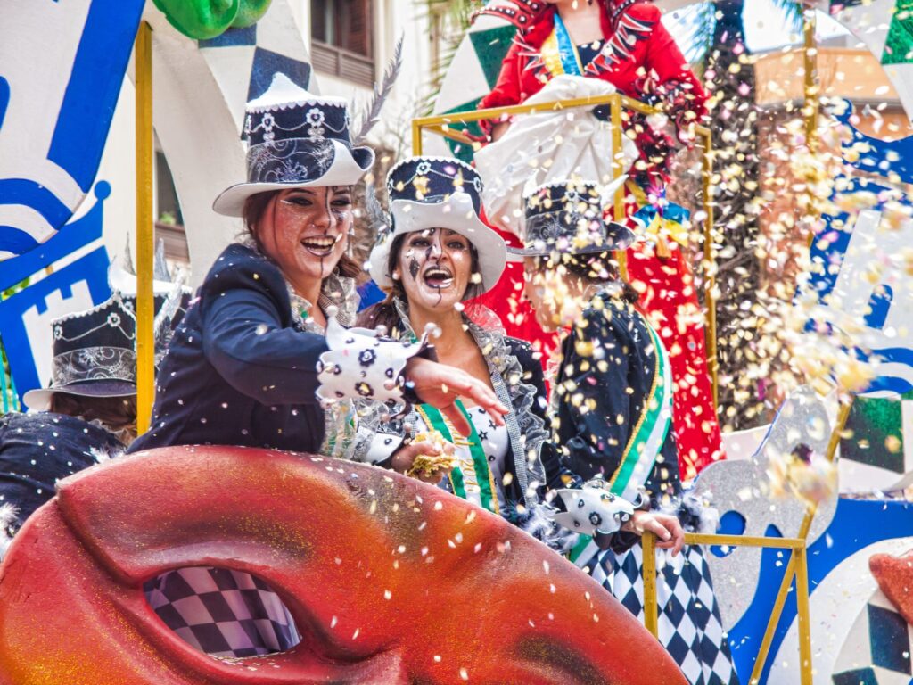 Women in costume throwing confettis off a Mardi Gras Float