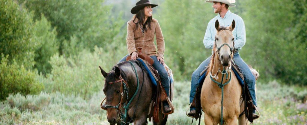 couple riding horses through the forest