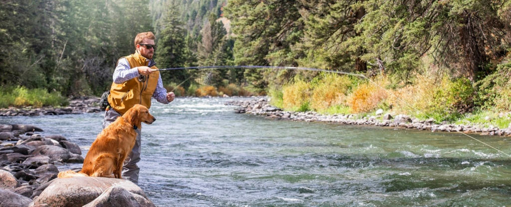 man fly fishing with dog beside him