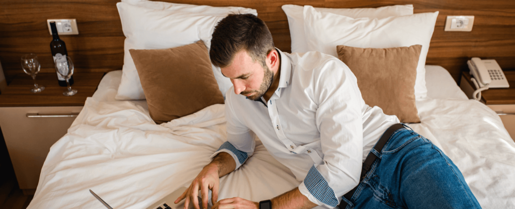 man working on laptop in bed