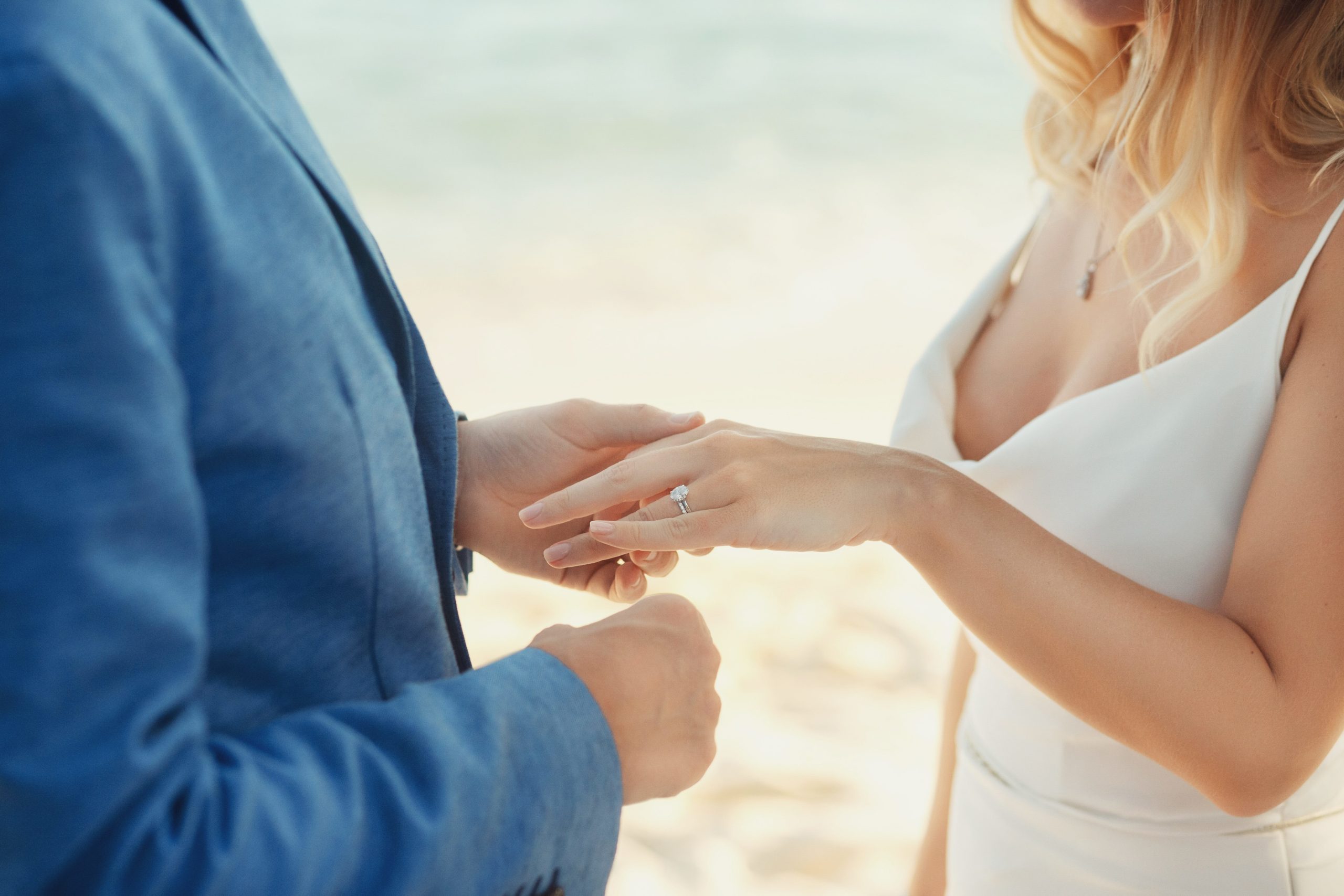 Groom in blue suit puts wedding ring on bride's hand