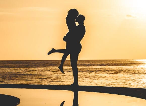 silhouette of couple kissing on beach