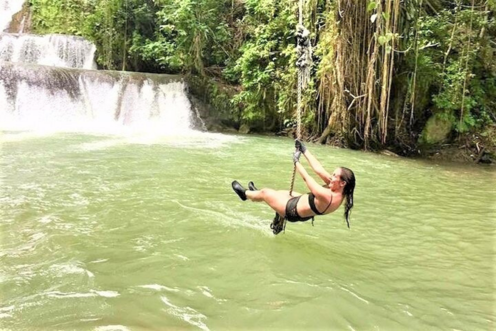 girl swings over pool of tropical water