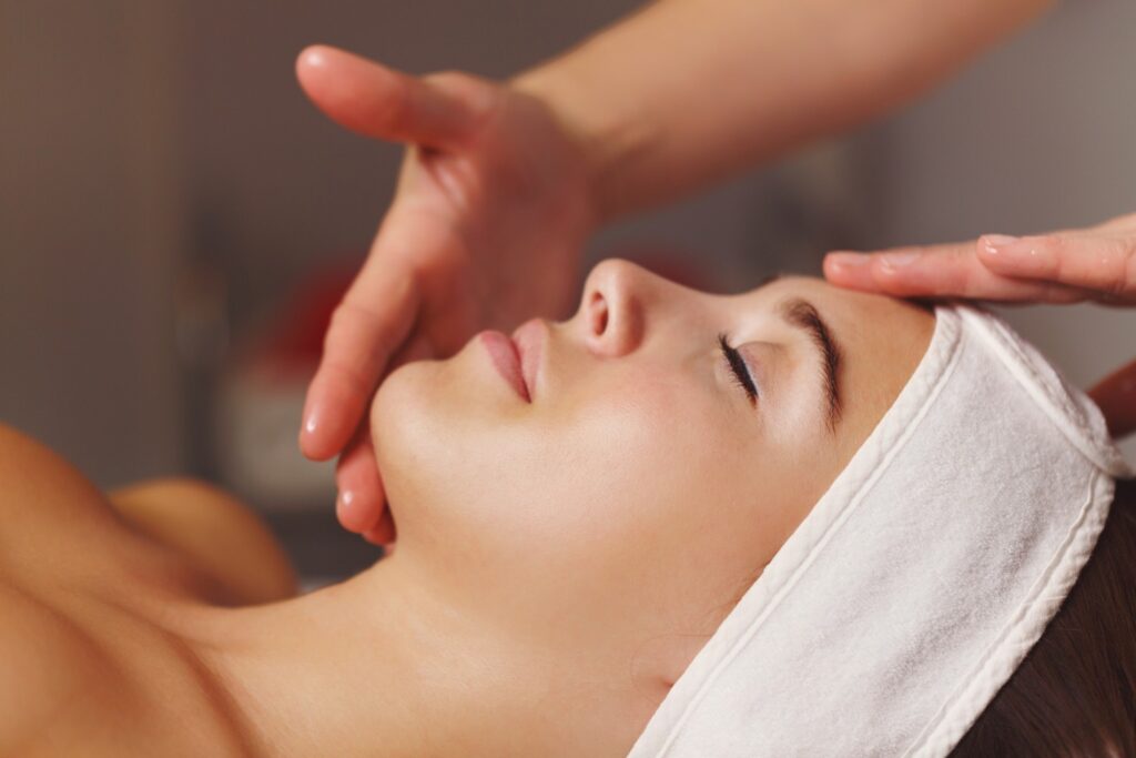 Spa treatment. Face massage. Massage of the forehead and chin zone of the client.