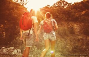 couple hiking and holding hands at sunset
