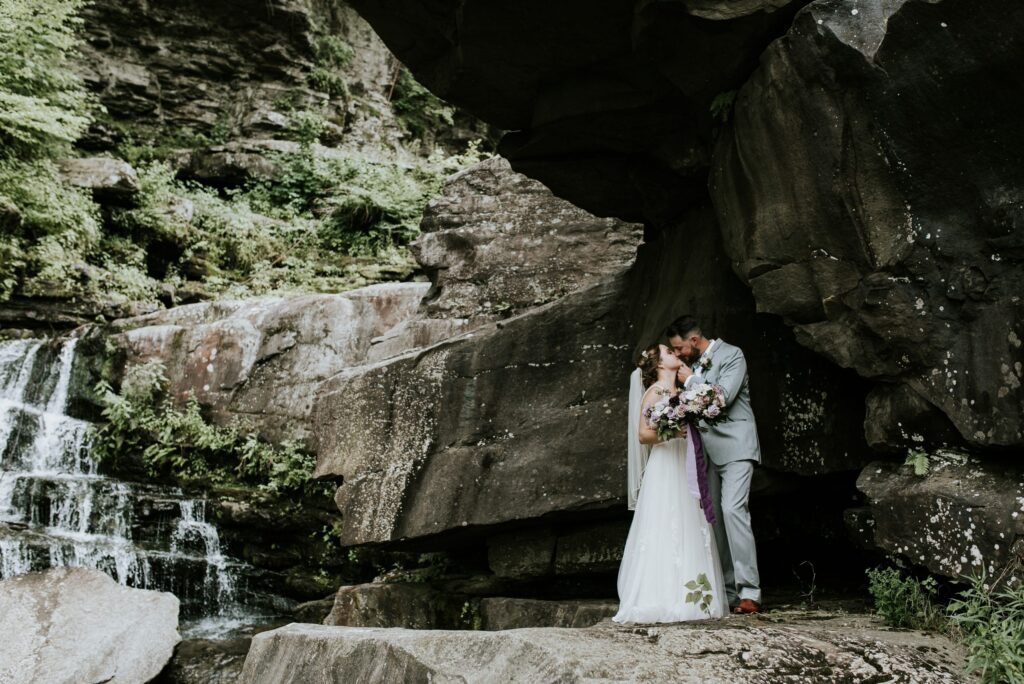 bride and groom kiss at the falls