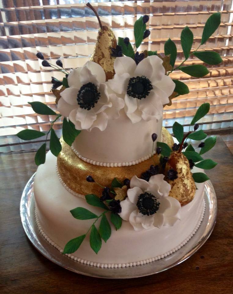 a white cake with flowers, leaves and golden pears