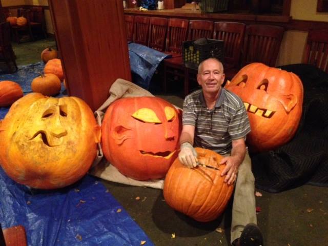 a man carves large pumpkins