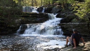 man sitting near waterfall