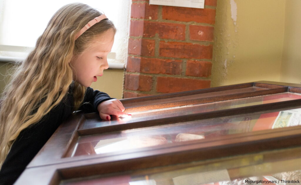 little girl looking and pointing at a museum exhibit