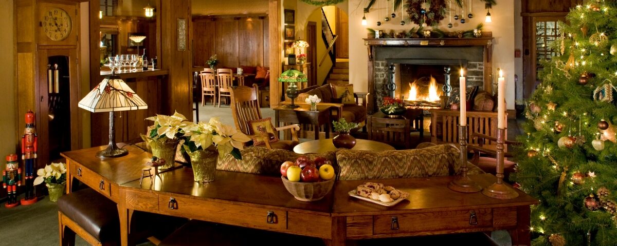 a hotel lobby decorated for christmas and warmed by a fireplace adorned with garland