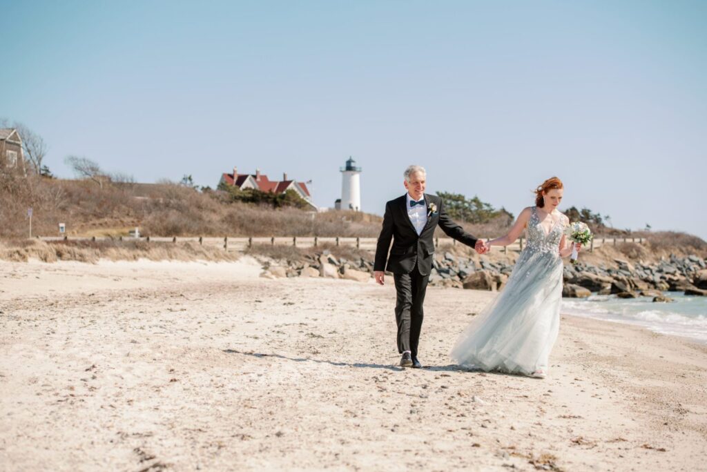 bride and groom hold hands on the beach