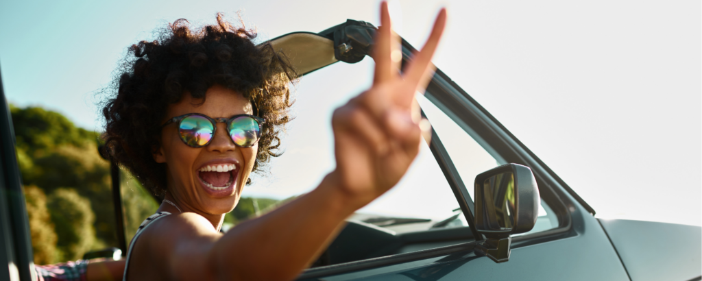 woman in convertible giving a peace sign