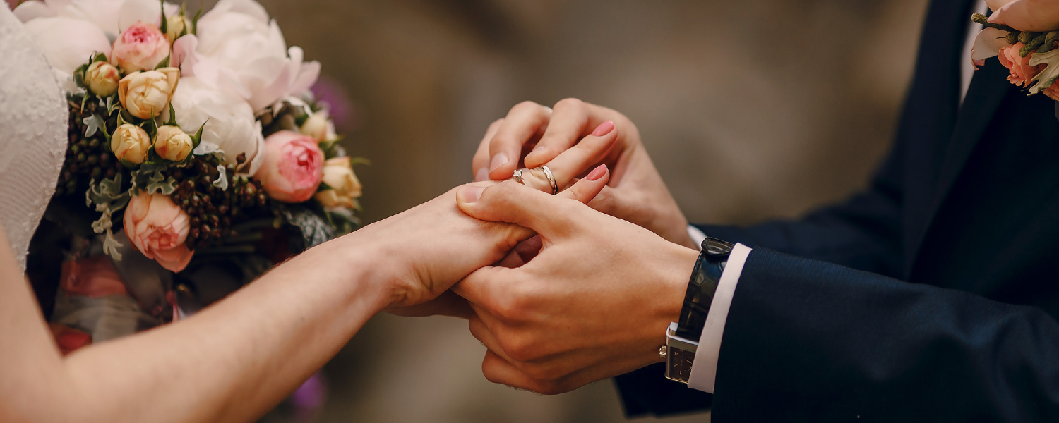Close-up of man sliding wedding ring onto woman's hand