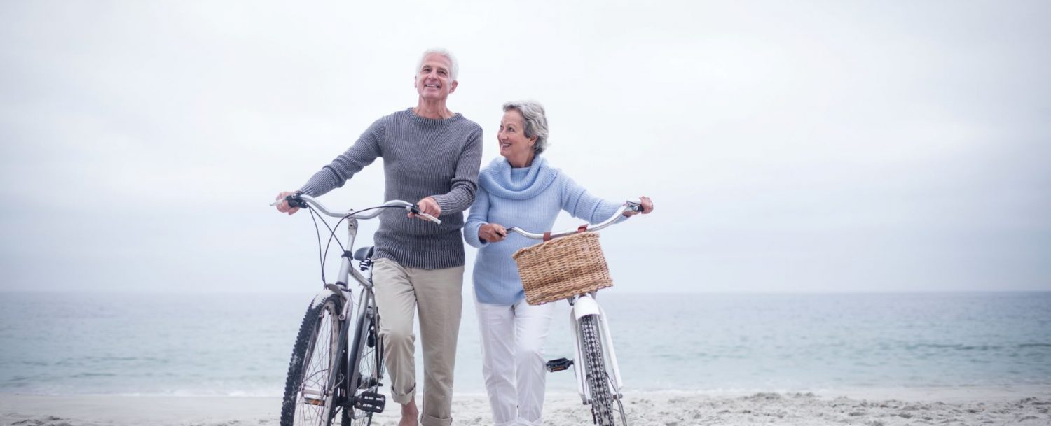 Senior couple having ride with their bike on the beach