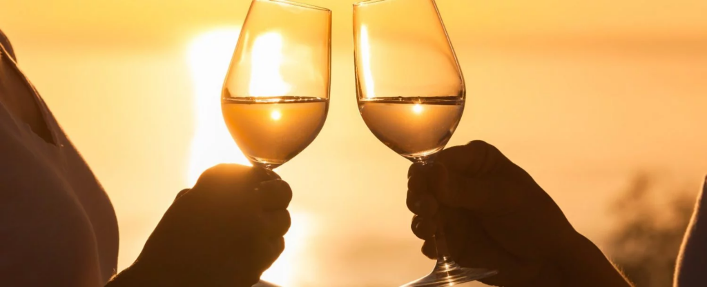 a couple holding wine glasses with a lake erie sunset in the background.