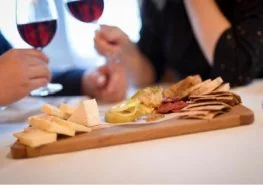 couple drinking wine in front of cheese plate