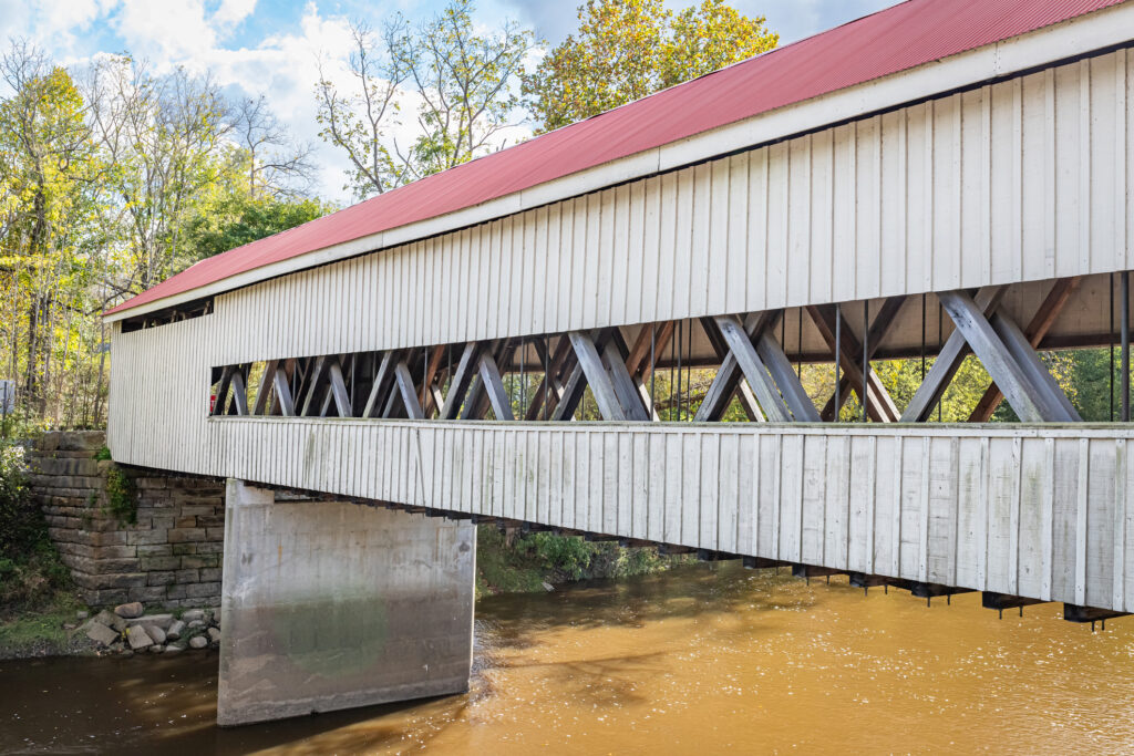The Mechanicsville Covered Bridge crosses Grand River during the Autumn leaf color change in Ashtabula County, Ohio. Discover more about Ashtabula in the travel guide to Ashtabua, OH.