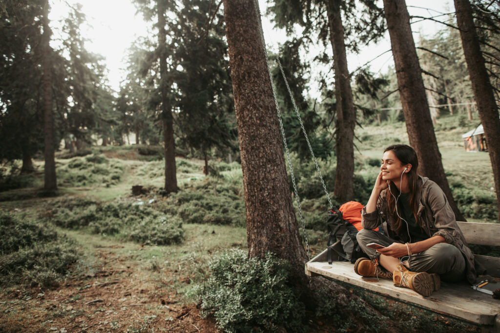 Young attractive woman listening music on smartphone in the forest
