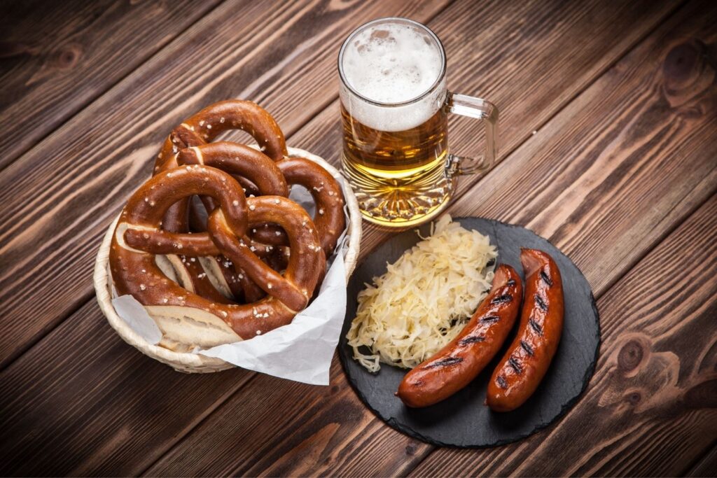Pretzels, sausage, and beer on a table.