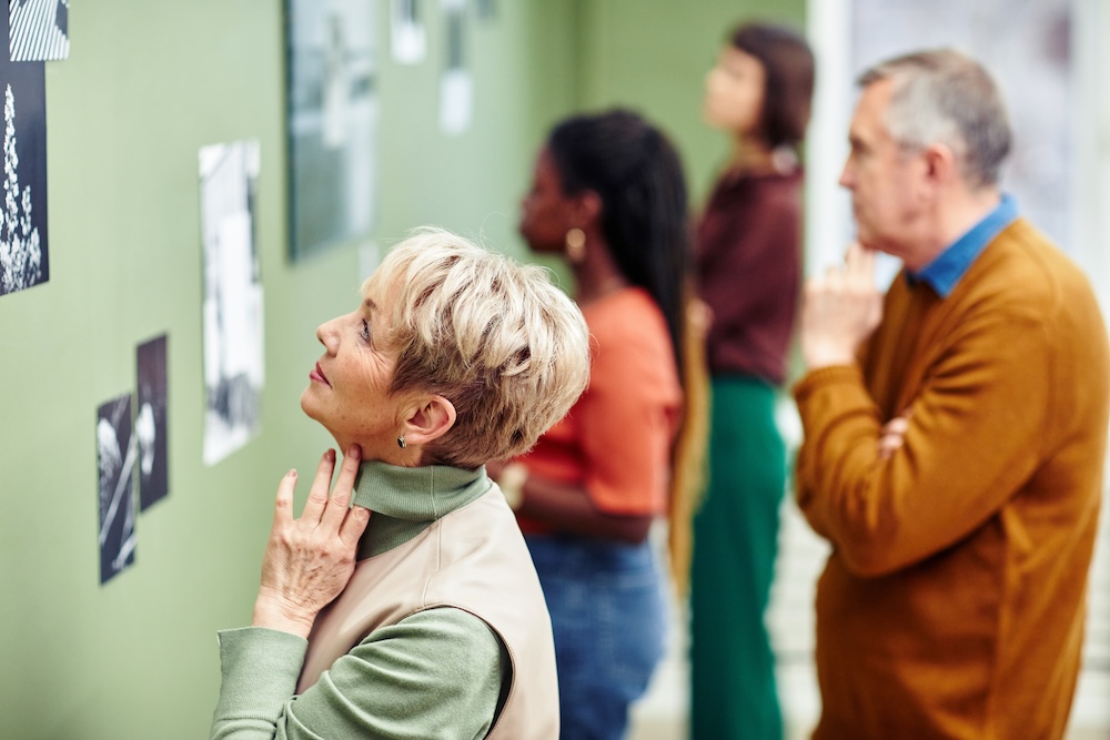 A group of people observing art pieces hanging in a gallery