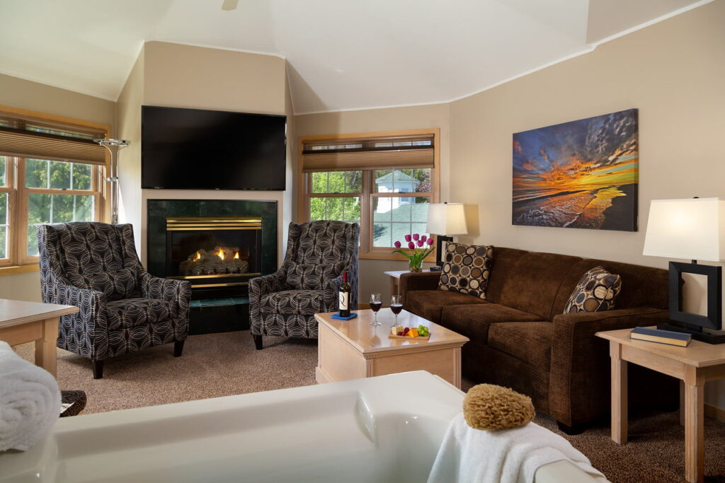 Vacation rental interior with a flat-screen TV, fireplace, and coffee table with two glasses of red wine