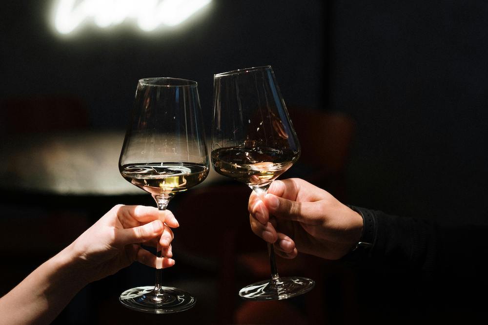 Closeup of two people bringing glasses of white wine together at a restaurant